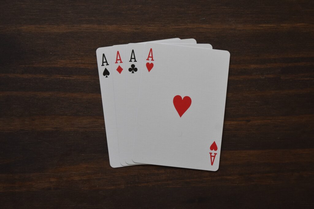 Top view of combination of four aces of different suits in poker on wooden table